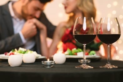 A group of people sitting at a long table with wine glasses, enjoying a social gathering.