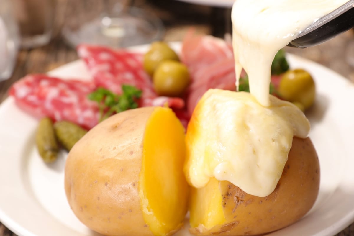 Pouring melted Raclette cheese over potatoes.