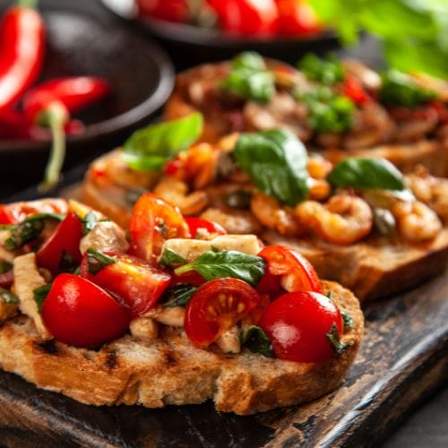 Colorful tomato and herb bruschetta on a wood plank.