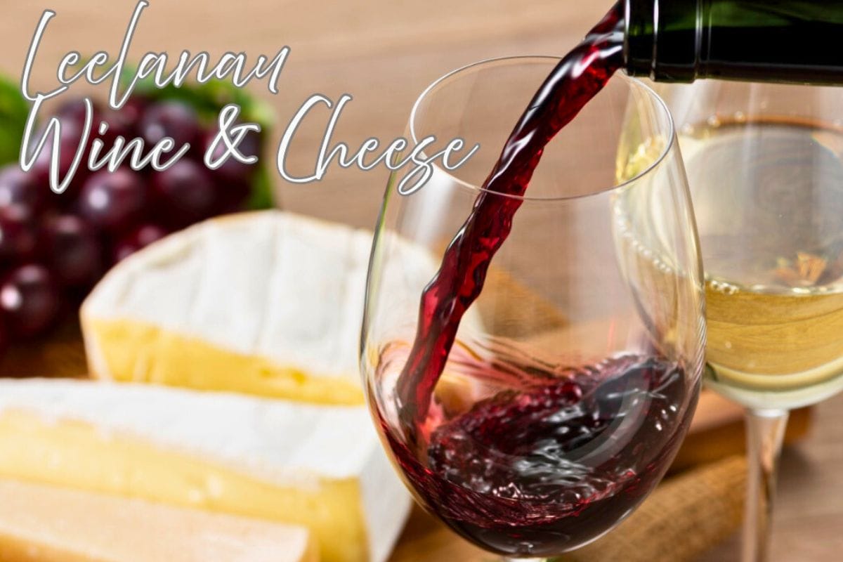 Pouring a glass of red wine with cheeses in the foreground