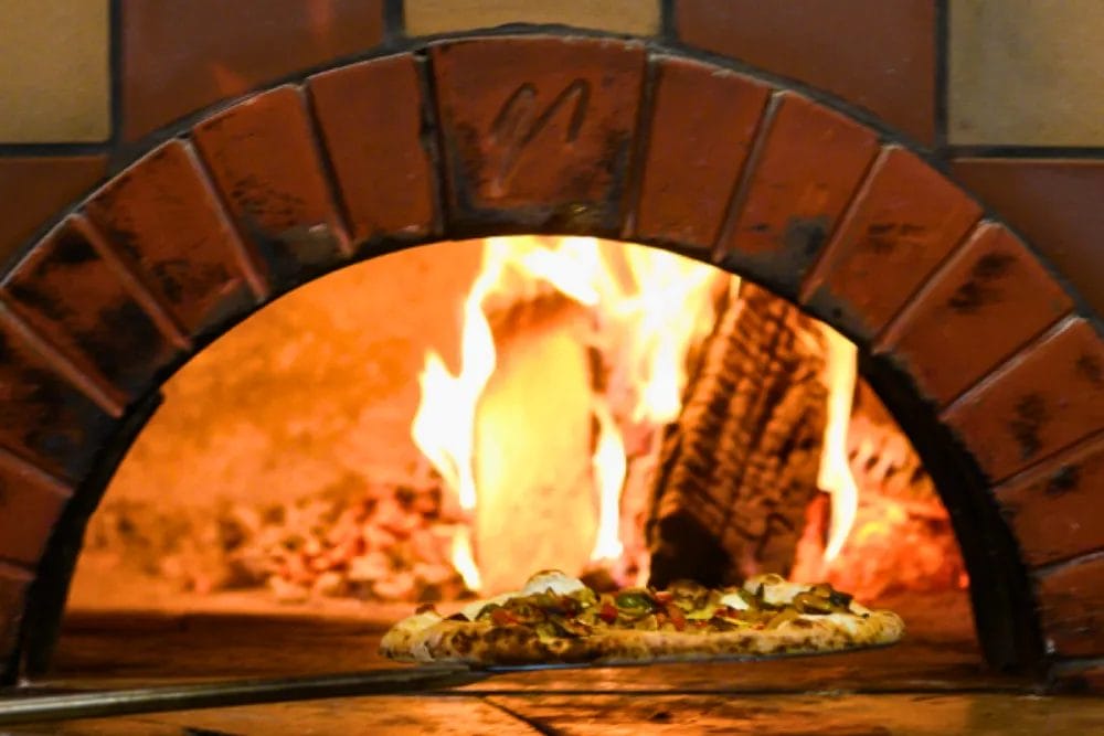 Fresh Mozzarella & Pizza Napoletana Cooking Class 4 Removing a pizza from our wood fired oven at Bistro Polaris