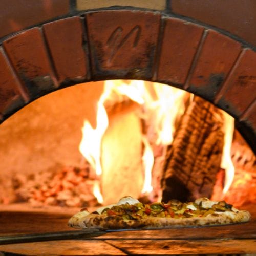 Pulling a pizza from a wood-fired oven.