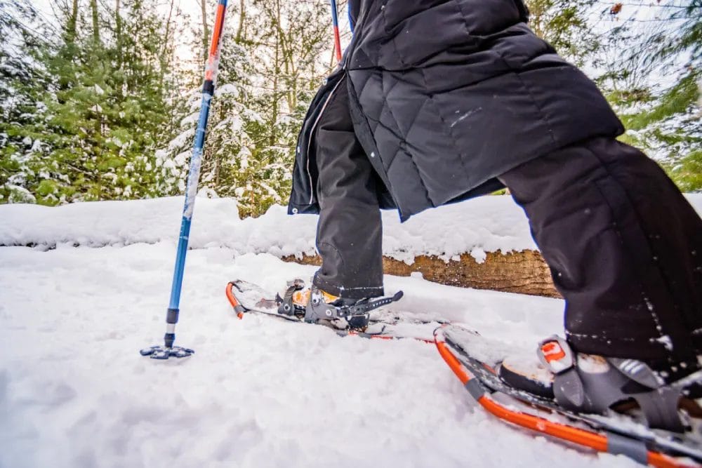 Person walking through snow close up with snowshoes on